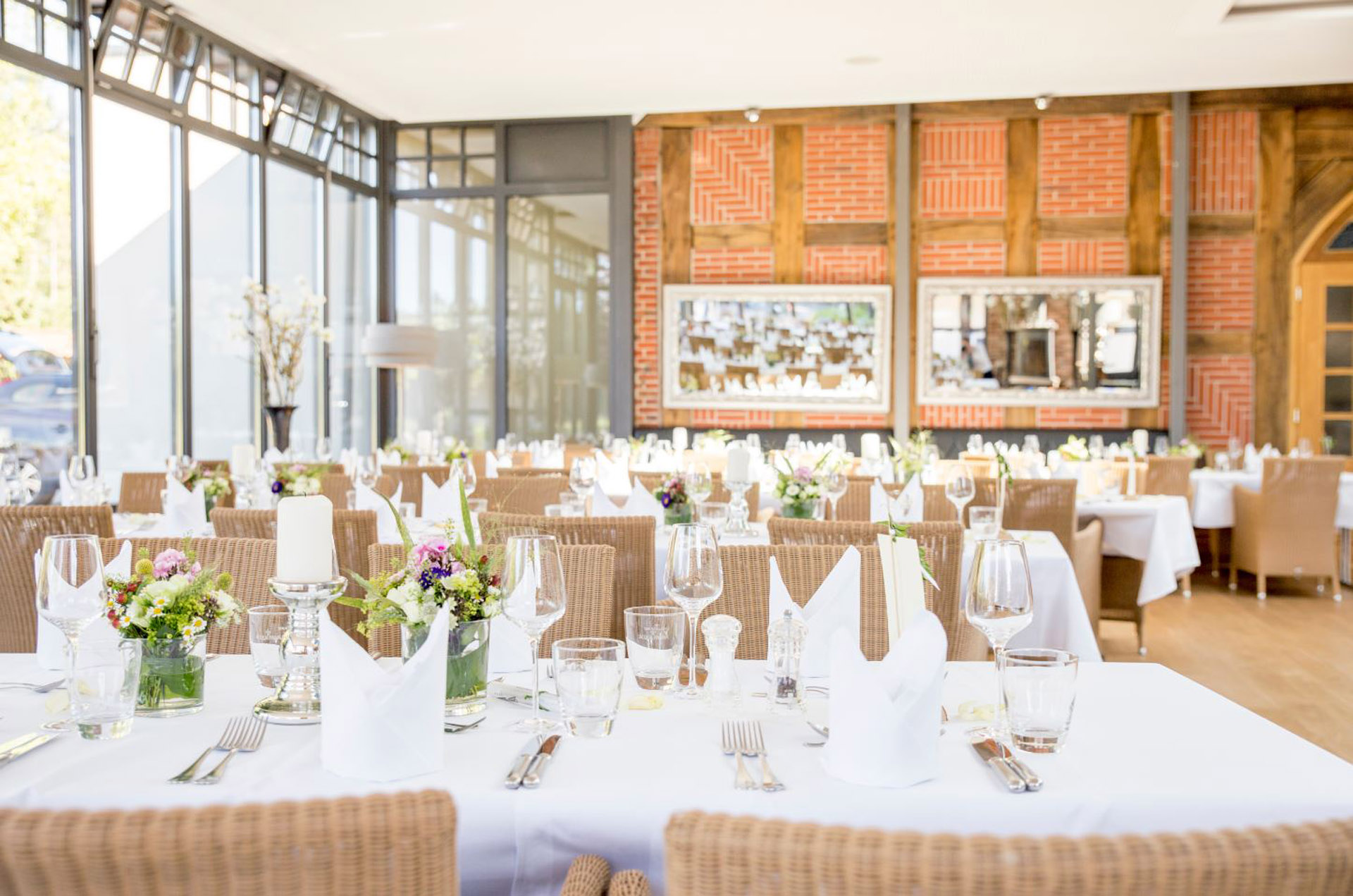 Eingedeckte Hochzeitstafel im Wintergarten auf Gut Altona vor der Fachwerkwand