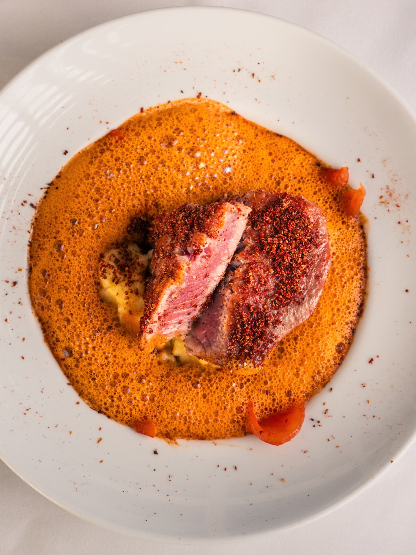 Rosa gebratenes Fleisch mit Gewürzkruste auf Kartoffelstampf und Paprikaschaum aus der Küche von Gut Altona
