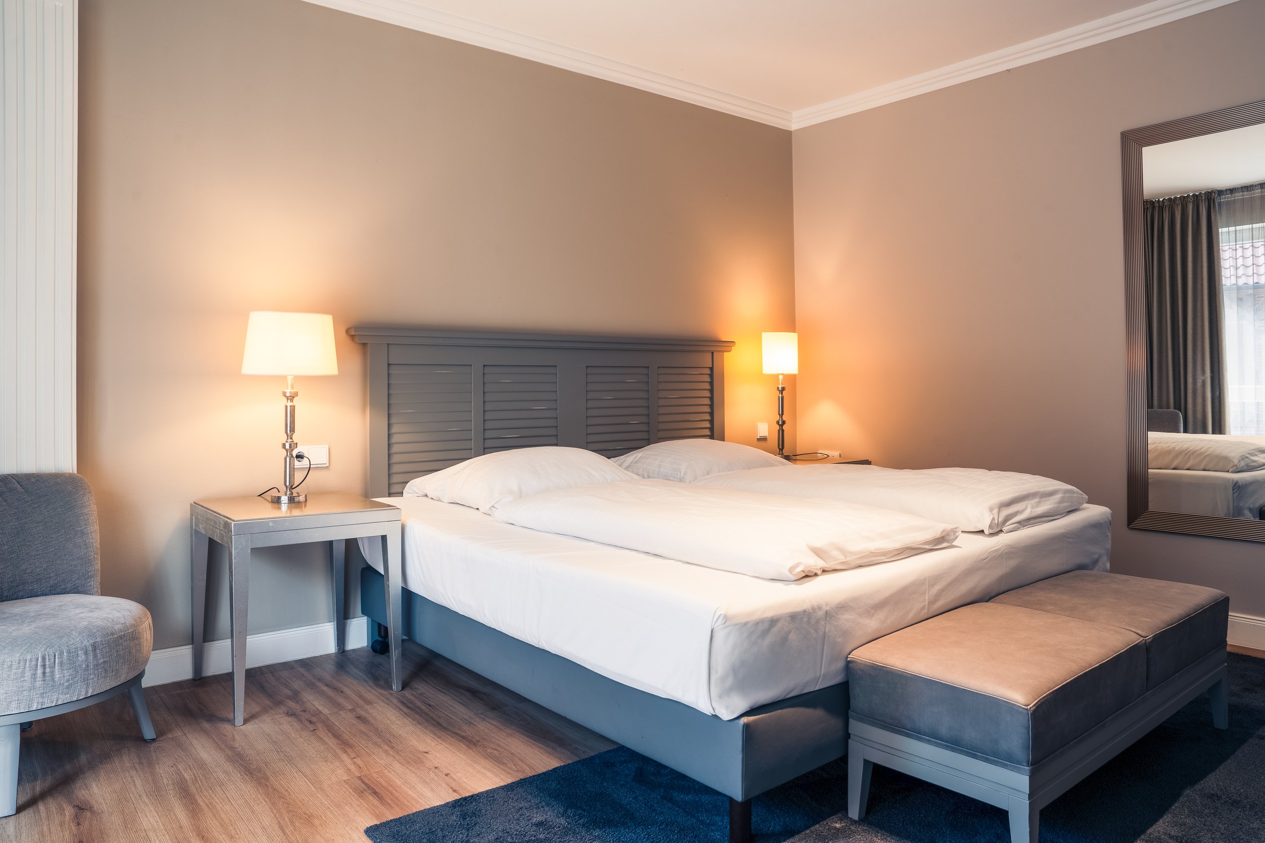Business-Doppelzimmer auf Gut Altona mit Doppelbett, Sessel und Spiegel