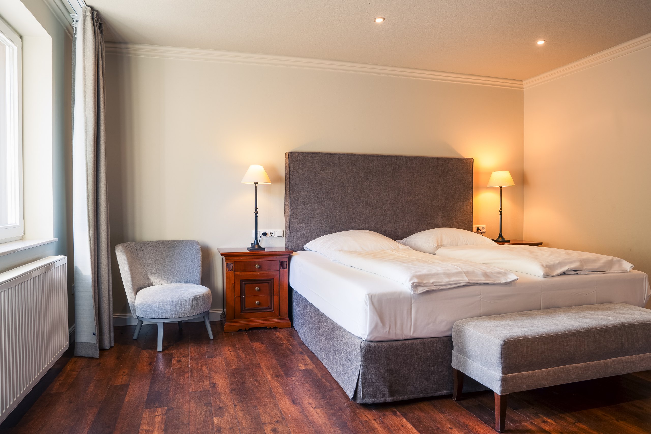 Familienzimmer auf Gut Altona mit Doppelbett, Sessel und Bank am Fenster