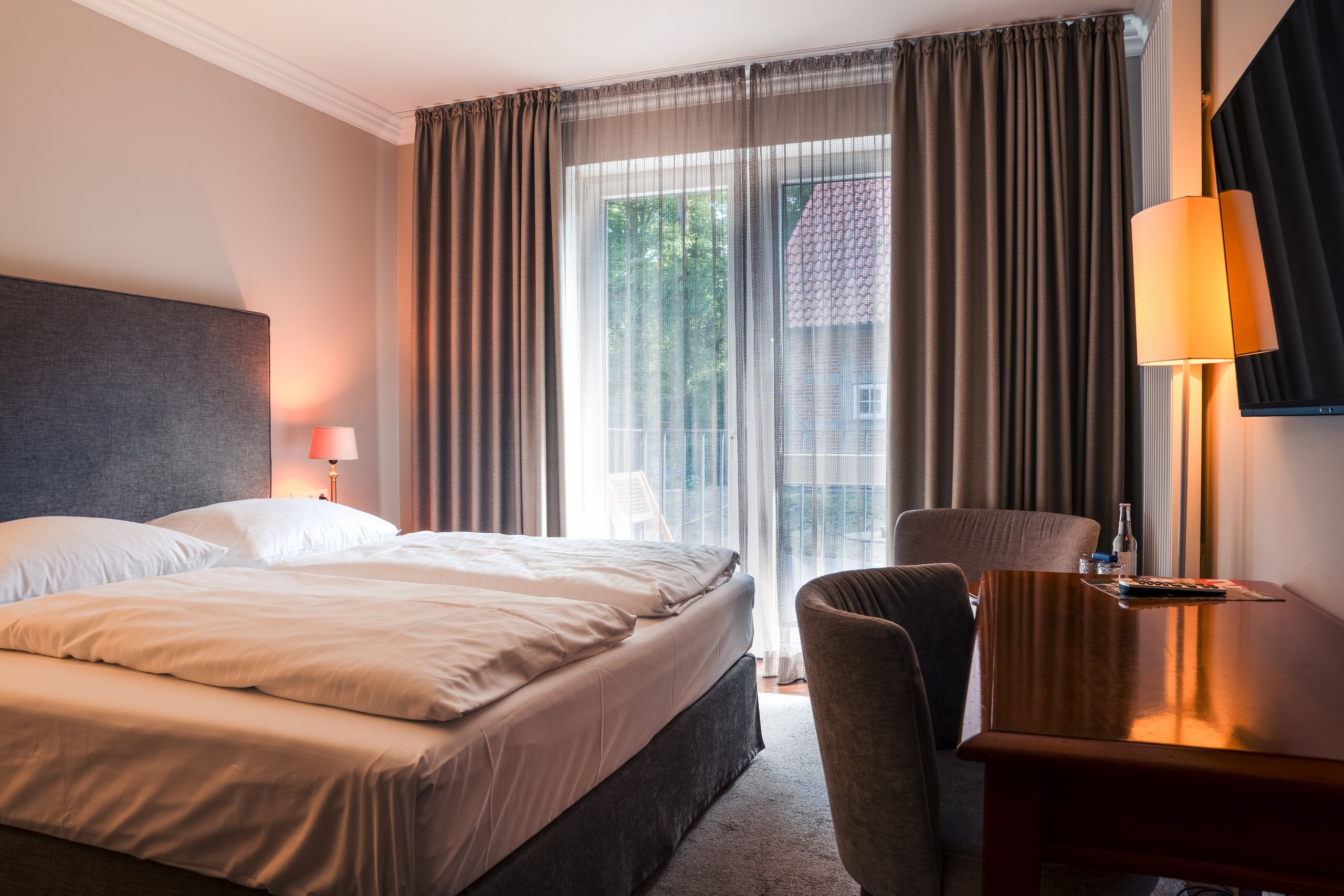 Komfort-Doppelzimmer auf Gut Altona mit Doppelbett, Sessel und Schreibtisch am Fenster