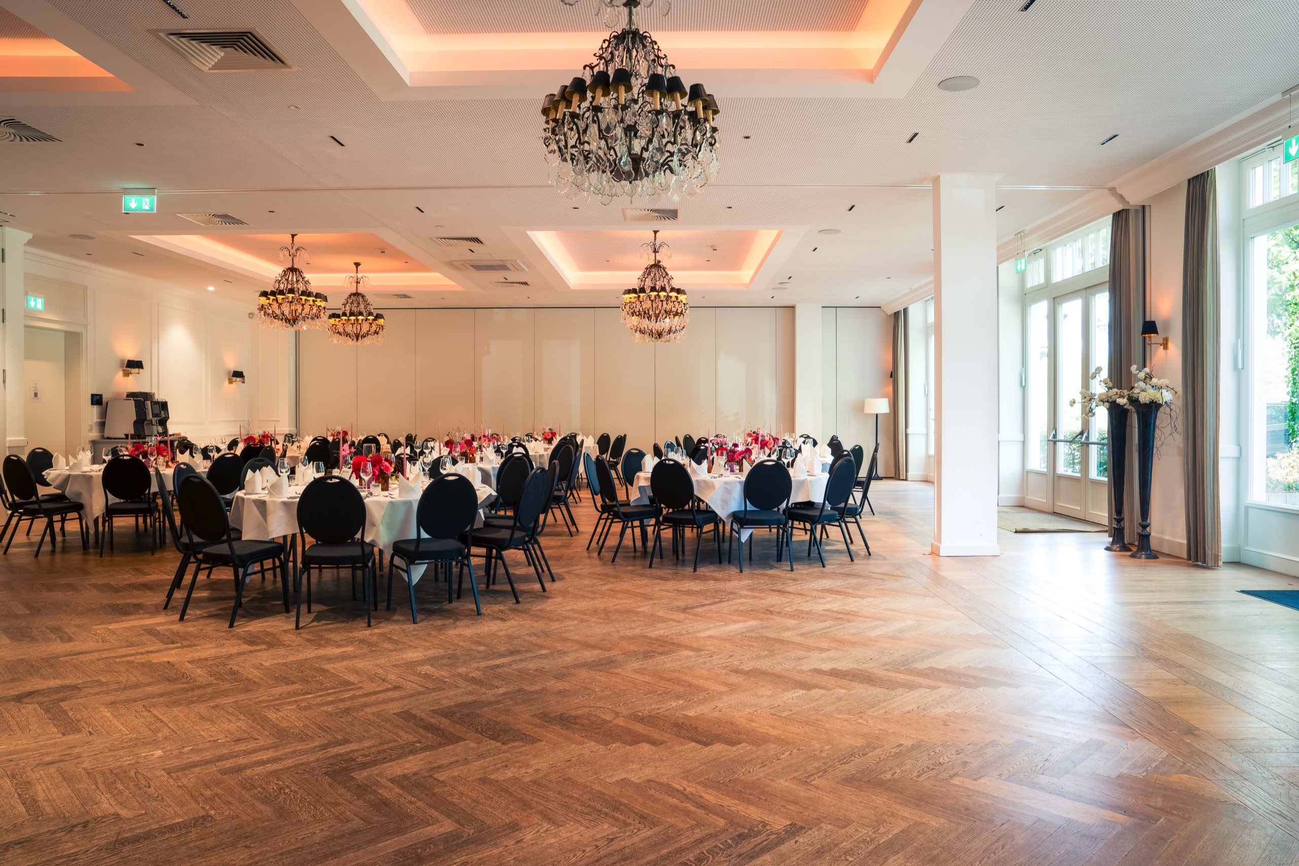 Festsaal auf Gut Altona mit runden Tafeln, Kronleuchtern, Eichenparkett und bodentiefen Fenstern
