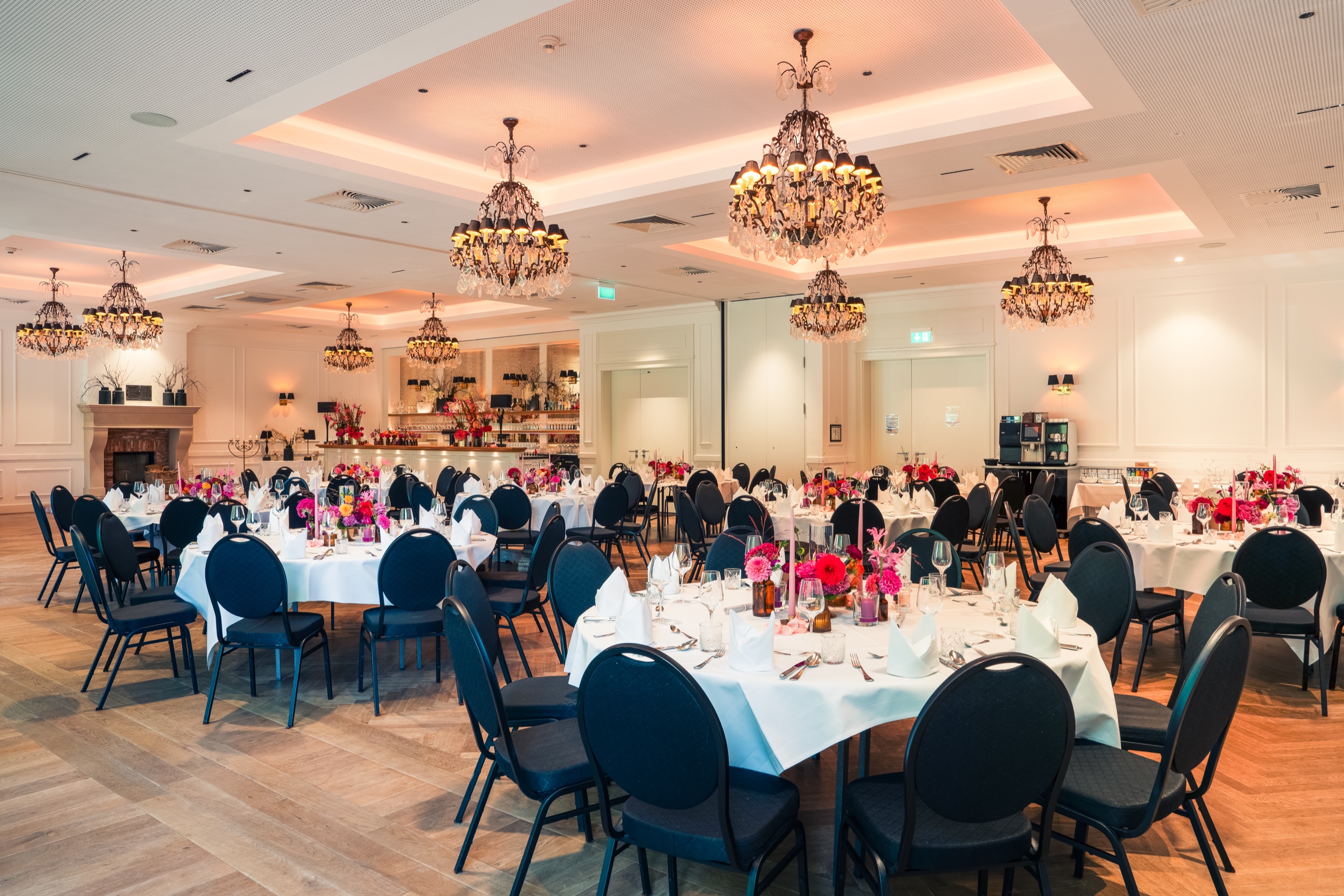 Runde Tafeln mit Blumenschmuck unter Kronleuchtern im Festsaal auf Gut Altona